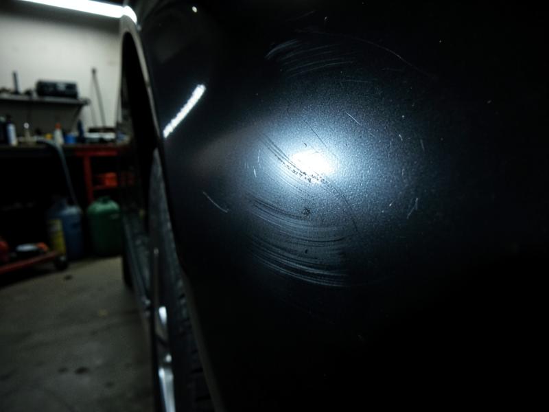 Donkere lak van een Range Rover Sport vol waskringen onder hard licht vóór de lakcorrectie