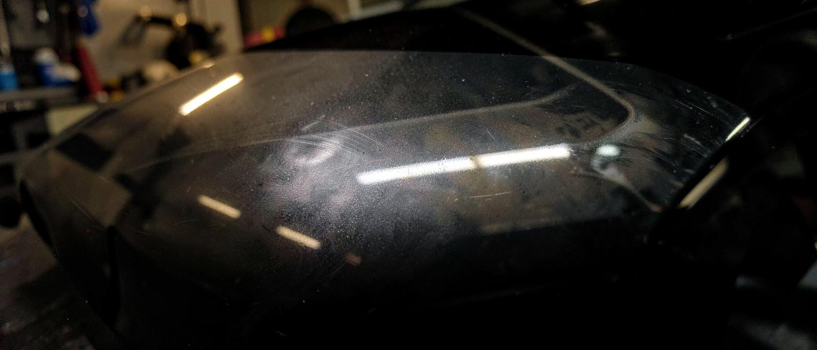 Polijstmachine op donkere metaallak, half nog vol waskringen en half spiegelglad